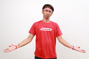 Asian young boy with red white ribbon for celebrating Indonesia independence day standing with confused gesture and face expression