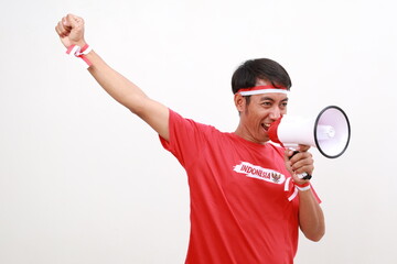 Asian man celebrating Indonesia Independence day, shouting using megaphone to sideways with fist hand. Isolated on white