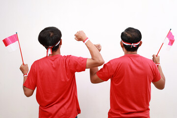 Poster - Back view of happy excited two Indonesian men raise their arms to celebrating Indonesia Independence Day together over white background.