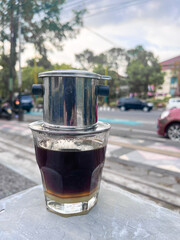 Vietnamese drip, Vietnamese coffee with condensed milk in glass cups and traditional metal coffee maker phin. Traditional method of making of vietnamese coffee. served on outdoor