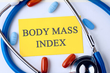 Wall Mural - Business concept acronym. BMI. Body Mass Index on a yellow business card in a composition with a stethoscope and pills