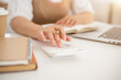 © bongkarn - A close-up image of a woman using a calculator, working at a desk indoor.