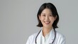 © Muschima - Realistic hyper-detailed portrait of a cheerful young Asian woman doctor smiling, highlighting her expertise and joy in delivering quality healthcare to her community. Background images that indicate