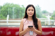 © bongkarn - A positive Asian female office employee with a phone in her hand is sitting in a seat on a sky train