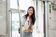 © bongkarn - A beautiful, positive Asian female traveler with a backpack and a camera is getting on a sky train.