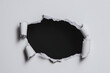 © digitalsync - Tattered Paper Reveal:  A torn hole in white paper reveals a black void. The edges of the paper are ragged and curled, suggesting a forceful breach. The dark background creates a sense of mystery and