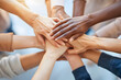 © Zape - Close-up of a diverse group of hands joined together in a circle, symbolizing unity and teamwork, set against a bright, neutral background.