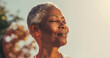 © john - Close up portrait of mature black woman with short gray hair standing in sunlight, peaceful and contemplative expression