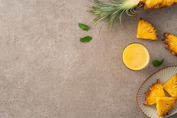 Wall Mural - Fresh delicious pineapple juice smoothie in glass cup on gray table background.