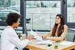 © LIGHTFIELD STUDIOS - Two people engrossed in conversation at table during job interview.