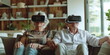 © Vasiliy - Elderly couple wearing VR headsets, sitting on a couch and holding hands