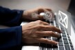 © izzuan - Close-up of a hands typing on a laptop keyboard with a several floating email icons. Sending and receiving emails concept.