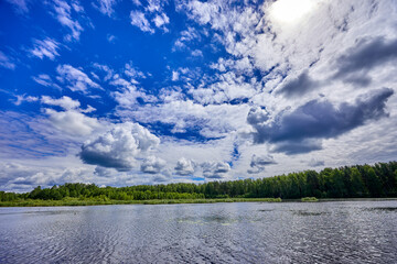 Beautiful summer river at sunny day with clouds reflection in the water