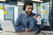 © Tetiana - Man recording podcast in office with headphones, microphone and smartphone