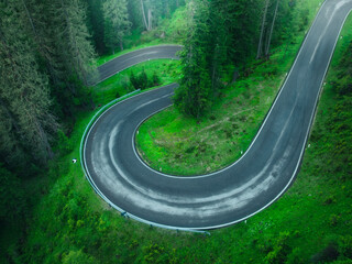 Wall Mural - aerial view of wet curvy road and green forest in summer