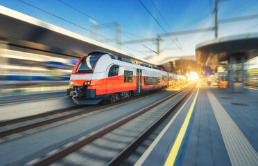 Wall Mural - High-speed passenger train moving at railway station at sunset