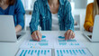 © TH_Stock - A team of professionals analyzes business charts and graphs on a desk, with two laptops open, focusing on data-driven decision-making in a modern office environment.