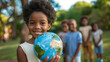 © Danica - Close-up of happy black children holding an earth globe in hand and looking at the camera, with a group standing behind them. African kids showing planet for world environment
