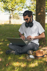 Wall Mural - Man working outdoors with laptop under a tree