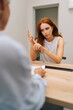 © dikushin - Vertical rear view of troubled woman patient talking to unrecognizable doctor sitting in clinic office, sharing complaints, asking professional specialist about treatment during visit at hospital.