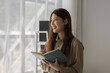 © Chadaporn - an Asian businesswoman is writing detail from the last meeting, there is a beautiful employee is smiling in the workplace, taking a note into the book witch is the first draft of report