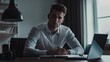 © GoodandEvil - Man in white shirt writing at desk with laptop
