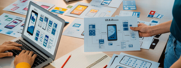 Panorama banner of startup UX developer or company employee design user interface or UI prototype for mobile application or website software with software display on laptop monitor in office. Synergic