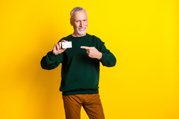 Wall Mural - Photo portrait of nice senior man hold point credit card dressed stylish green clothes isolated on yellow color background