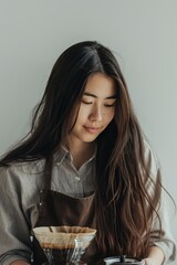 portrait of a female asian barista with long brown hair on grey background