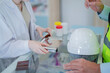 © ultramansk - A pharmacist prepares medicine for a construction worker on the counter of a pharmacy.