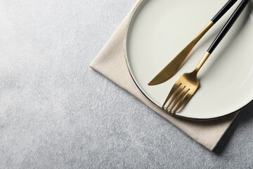 Wall Mural - Stylish golden cutlery, plate and napkin on grey table, top view. Space for text