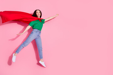 Poster - Full length photo of adorable lovely girl wear green t-shirt superhero cape jumping high empty space isolated pink color background