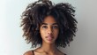 © sarana - Woman with Natural Hair: A woman with natural, curly hair styled beautifully, with a simple background to highlight her features.