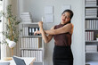© amnaj - Young businesswoman stretching at her office desk, surrounded by typical items. Natural light highlights the background