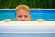 © Cavan Images - Boy peeking over edge of swimming pool