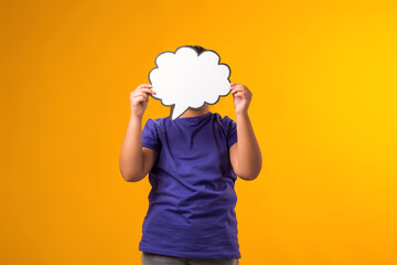 Smiling girl holding cloud bubble card in front of face over yellow background. Dreaming concept