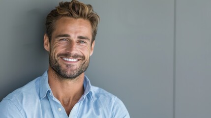 Wall Mural - A man with a blue shirt and a beard is smiling