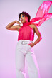 © LIGHTFIELD STUDIOS - A beautiful African American woman poses actively in a pink top and white pants against a vibrant backdrop.