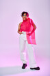 © LIGHTFIELD STUDIOS - African American woman poses gracefully in white pants and pink top on vibrant backdrop.