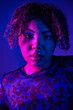 © LIGHTFIELD STUDIOS - African American woman with curly hair in leopard print shirt posing on vibrant backdrop.