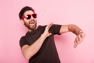 Wall Mural - Photo of eccentric man with stylish bristle dressed brown t-shirt in sunglass dancing in night club isolated on pink color background