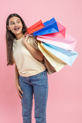 Wall Mural - Amazed woman wearing casual T-shirt and jeans visiting fashionable boutique holding shopping bags