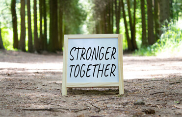 Wall Mural - Stronger together symbol. Concept word Stronger together on white chalk background. Beautiful forest background. Business and Stronger together concept. Copy space