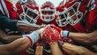 © Sergey - A group of high school football players in red uniforms huddle together in a show of team unity, placing their hands on top of each other's.