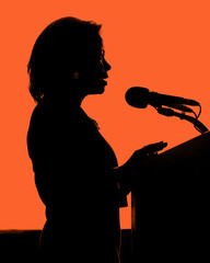 side view semi-silhouette profile of an African American woman speaking at a podium, red background