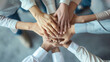 © Maksym - Business team from above, hands stacked together in a gesture of unity and cooperation. Office setting with diverse professionals showing collective strength and teamwork