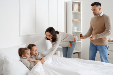 Canvas Print - Parents putting their ill little daughters in bed at home