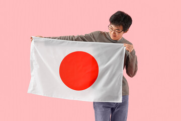 Sticker - Young Asian man with flag of Japan on pink background