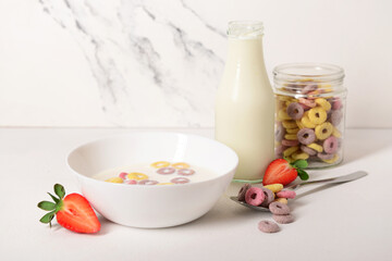 Sticker - Bowl of colorful sweet cereal rings with milk and cut strawberry on white background