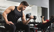© Prostock-studio - Arab muscular man doing biceps workouts with dumbbells in gym, copy space